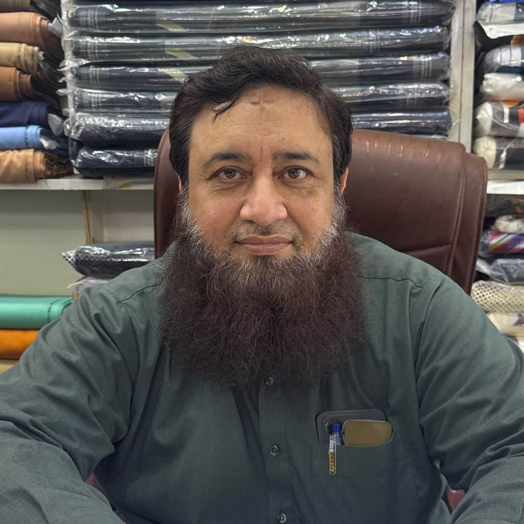 Shahzad Ahmad, proprietor of Shahzad Cloth House, at the shop counter in Sialkot
